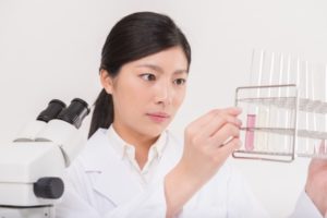 試験管を見る白衣の女性